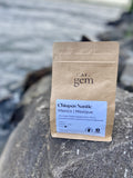 A kraft paper pouch of Cafe Gem Chiapas Nantic Mexico specialty coffee sits outdoors.